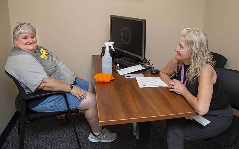 Employment specialist seated at a desk across from individual who is receiving supported employment