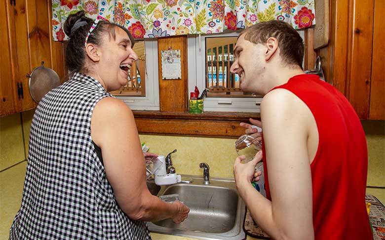 Young developmentally disabled man learning to do dishes with support person