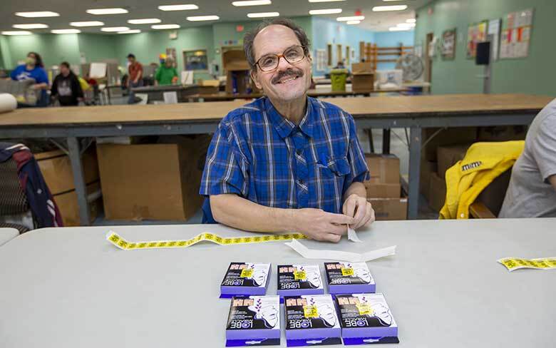 Man attaching labels to a product as part of the Fulfillment Services Packaging and Assembly program at Abilities