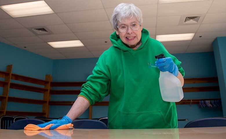 Woman sanitizing a table as she learns about environmental hygiene at the Abilities Health and Wellness Program