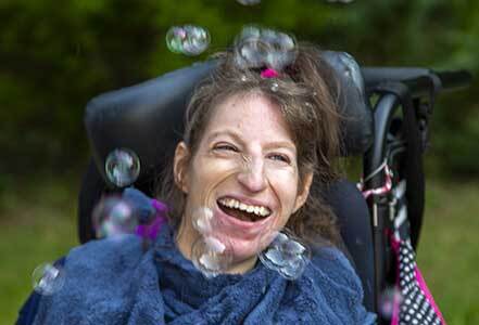 Woman with medical special needs laughing at bubbles in the air at Abilities of NW Jersey Medical Day Program