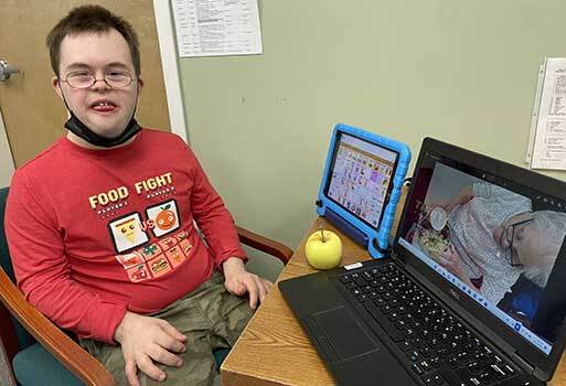 Young man with special needs sitting at a desk working on speech and communication