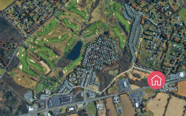 Aerial view of a residential community and surrounding neighborhood, showing housing developments, roadways, open green space, and a location marker indicating a residential services site.